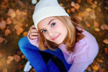 Genç ve güzel bir kız Altın yaprağı ile yere oturuyor. Sonbahar moda, güzellik.