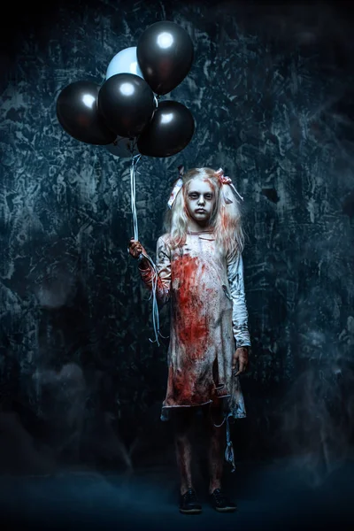 A scary girl holding balloons. Halloween. Horror film.