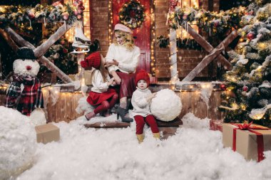 Anne ile çocuk Noel için dekore edilmiş bir kardan adam evinin önünde olun. Mutlu Noeller ve mutlu yeni yıl.