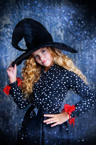 Beautiful child girl in a costume of a witch over grunge background. Halloween party.