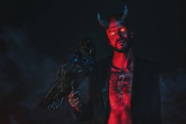 Siyah bir kuzgunla kötü bir iblisin portresi. Korku filmi, kabus. Cadılar Bayramı.