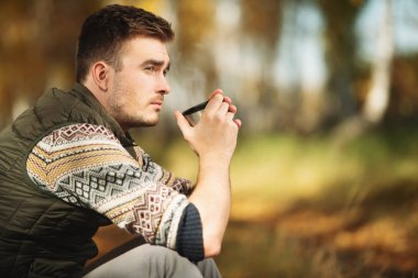 Yakışıklı bir adam doğal olarak oturan ve çay içme. Özgürlük, yaşam tarzı, sonbahar.