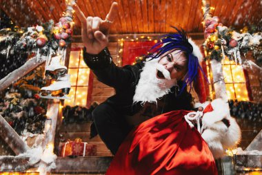 Sheerful punk Santa fools around near his house with a bag of gifts in his hands. clipart