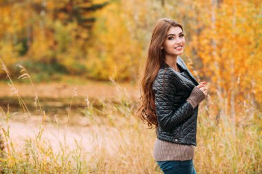Sonbahar ormanında deri ceket giyen güzel bir genç kadının portresi. Yaşam tarzı, sonbahar modası, güzellik. 