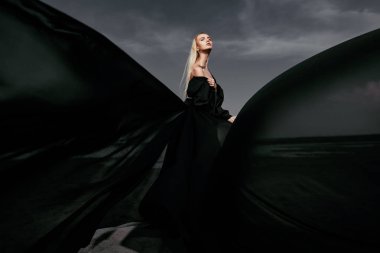 Tam uzunlukta portre güzel bir Gotik kadının uzun siyah elbise poz açık. Güzellik, moda.