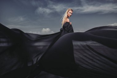 Tam uzunlukta portre güzel bir Gotik kadının uzun siyah elbise poz açık. Güzellik, moda.