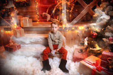 Şirin çocuk oğlan evinin Noel için dekore edilmiş verandada oturuyor. Mutlu Noeller ve mutlu yeni yıl.