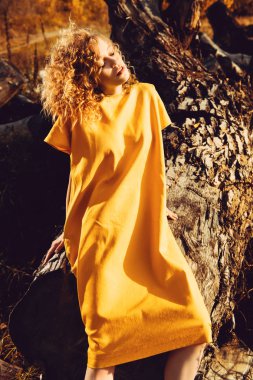 Sarı elbiseli kıvırcık saçlı çekici bir genç kızın portresi. Moda, güzellik.