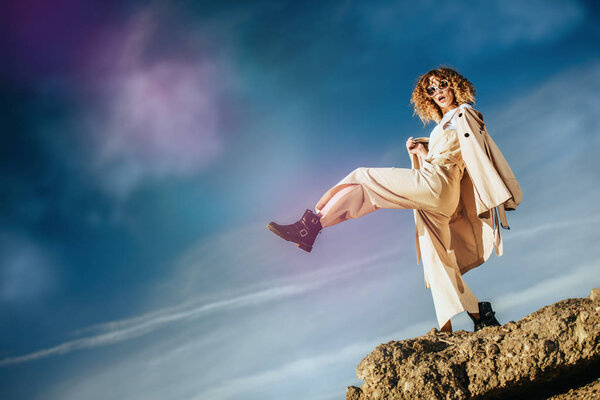 A charming young girl with curly fair hair in fashionable clothes. Fashion, beauty.