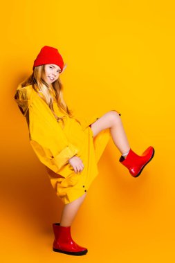 Parlak bir moda kız yağmurluk ve bir şapka. Çocuklar için sonbahar moda.