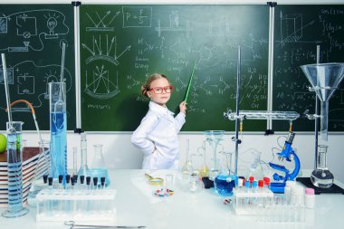 Zeki kız öğrenci tarafından bir kara tahta kimya dersi üzerinde duruyor. Eğitim kavramı.