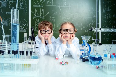 Sürpriz kız ve erkek bilim adamları laboratuarda deney yapıyorlar. Eğitim kavramı. Erken çocuk gelişimi.