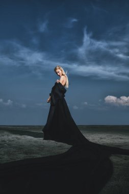 Tam uzunlukta portre güzel bir Gotik kadının uzun siyah elbise poz açık. Güzellik, moda.