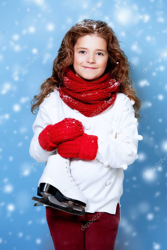A portrait of a pretty young girl holding skates. Winter fashion for kids, beauty, active and healthy lifestyle.