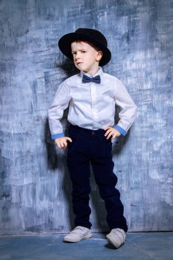 Küçük yakışıklı şık giysiler ve bir şapka. Babam gibi olmak. Çocuk moda. Tam uzunlukta portre.