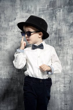 Küçük yakışıklı şık giysiler ve güneş gözlüğü. Babam gibi olmak. Çocuk moda.