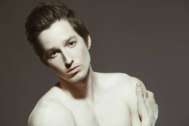 İnce beden stüdyoda poz ile seksi genç bir adam portresi. Gri arka plan. Erkek Sağlığı.