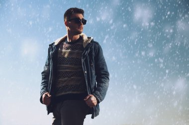 Bir ceket ve güneş gözlüğü takan yakışıklı acımasız bir adam. Moda Erkekler için. Sonbahar, kış.