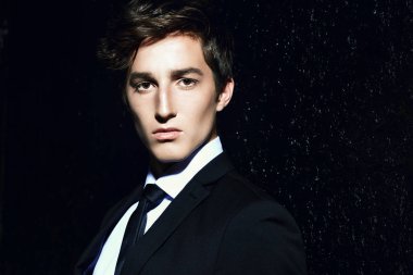 Siyah takım elbise ve beyaz gömlek siyah arka plan üzerinde poz yakışıklı bir genç adam portresi. Erkek güzellik, moda. Saç şekillendirme.
