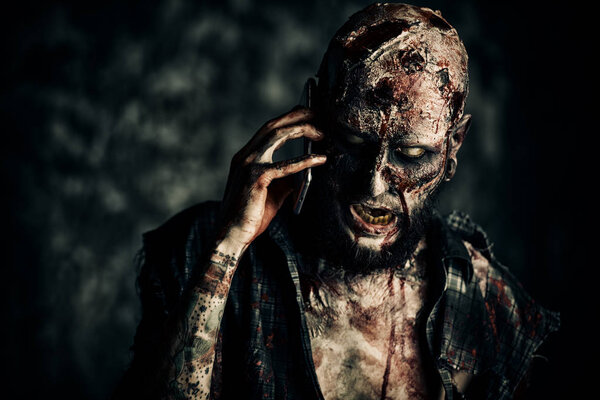 Жуткий страшный зомби разговаривает по мобильному телефону. Хэллоуин. Фильмы ужасов
.
