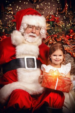 Mutlu bir genç kız Noel Baba yakınındaki bir hediye ile evde oturuyor. Mutlu Noeller ve mutlu yeni yıl.