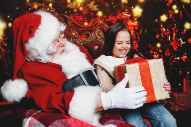 Mutlu bir genç kız Noel Baba yakınındaki bir hediye ile evde oturuyor. Mutlu Noeller ve mutlu yeni yıl.