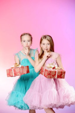 İki sevimli küçük kız ellerinde hediye kutuları ile güzel festival elbiseler giymiş. Çocuk moda kavramı.