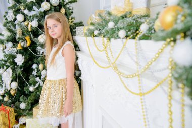 Noel ağacı yakınındaki zarif parlak elbise ayakta kız güzel çocuk. Noel mucizeler. Lüks Noel dekorasyon.