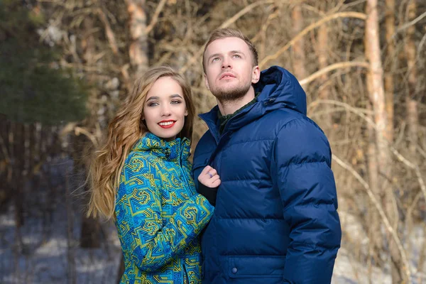 Couple of young people is walking in winter clothes in the park. Winter fashion. Down jacket.