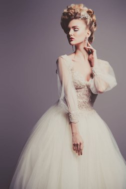 Kabarık elbise ve stüdyoda gri arka plan üzerinde poz soğuk bir güzel Bayan portresi. Güzellik, kozmetik, saç modeli, moda.