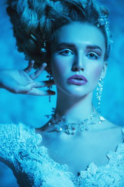 Stüdyoda mavi arka plan üzerinde poz güzel soğuk bir Bayan portresi yakından. Güzellik, kozmetik, saç modeli.