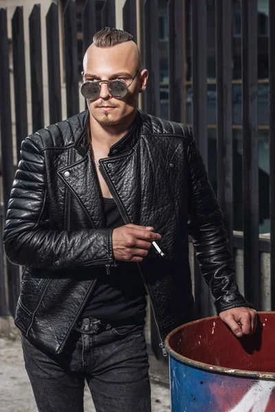 Sokakta sigara serseri bir adam portresi. Moda, alt kültür.