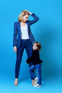 Anne ve oğlu stüdyoda poz ve rahat kıyafetler giyiyor. Aile, moda.
