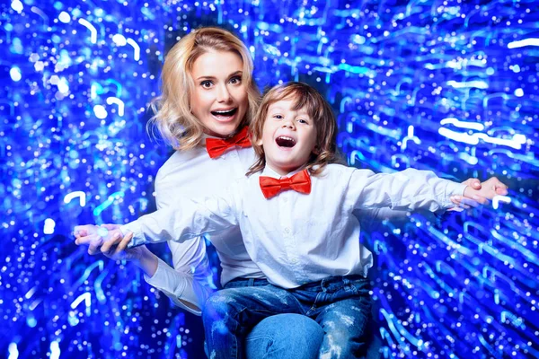 Portrait of a happy mom with her little son wearing white shirts and bow ties. Merry Christmas and Happy New Year.