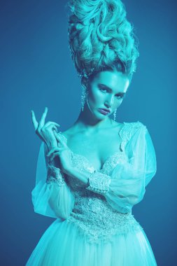 Stüdyoda mavi arka plan üzerinde poz güzel soğuk bir Bayan portresi yakından. Güzellik, kozmetik, saç modeli.