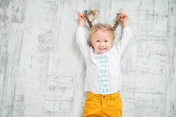 Neşeli bir kız yerde yatıyor. Çocuklar için moda.