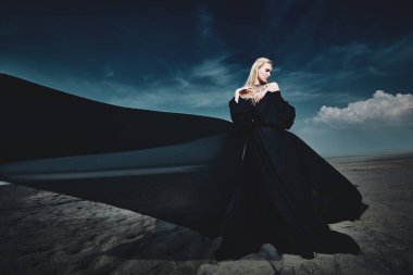 Tam uzunlukta portre güzel bir Gotik kadının uzun siyah elbise poz açık. Güzellik, moda.