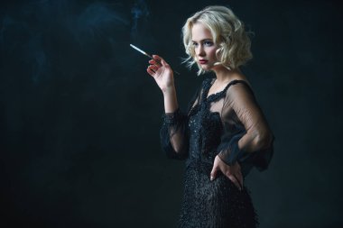 Güzel bir sarışın Bayan sigara içiyorum. Gece elbisesi. Moda, güzellik.