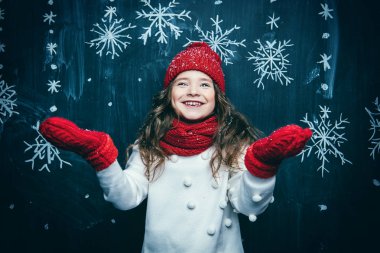 Bir şapka, bir kazak ve bir eşarp giyen genç ve güzel bir kız portresi. Çocuklar, güzellik için kış modası.
