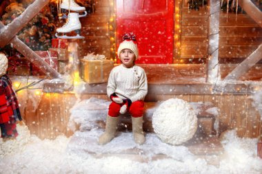 Şirin çocuk çocuk Noel Baba'nın sihirli ev verandada oturuyor. Mucize zamanı. Mutlu Noeller ve mutlu yeni yıl.