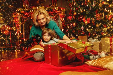 Anne ve oğlu, Noel için dekore edilmiş ev bir hediye kutusu açma altındadır. Aile mucize zamanı. Mutlu Noeller ve mutlu yeni yıl.