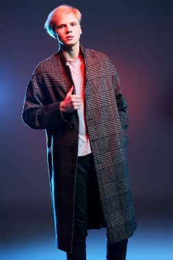 Vogue yakışıklı bir erkek model gri arka plan üzerinde kareli ceket daimi bir kadeh. Tam uzunlukta portre. Erkek güzelliği, moda. 