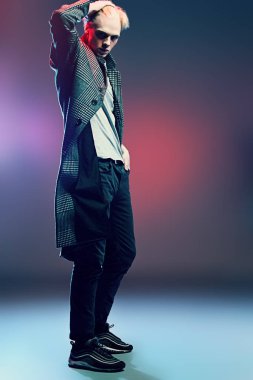 Vogue yakışıklı bir erkek model gri arka plan üzerinde kareli ceket daimi bir kadeh. Tam uzunlukta portre. Erkek güzelliği, moda. 