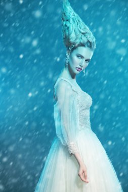 Kabarık elbise ve stüdyoda mavi arka plan üzerinde poz soğuk bir güzel Bayan portresi. Güzellik, kozmetik, saç modeli, moda.