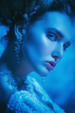 Stüdyoda mavi arka plan üzerinde poz güzel soğuk bir Bayan portresi yakından. Güzellik, kozmetik, saç modeli.