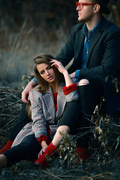 Autumn fashion. Beautiful fashionable couple on yellowed autumn grass and leaves.