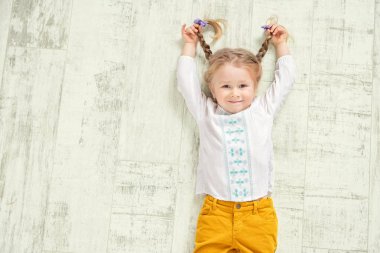 Neşeli bir kız yerde yatıyor. Çocuklar için moda.