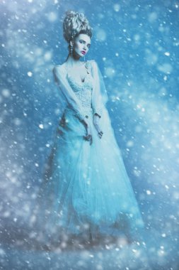 Kabarık elbise ve stüdyoda mavi arka plan üzerinde poz soğuk bir güzel bayan bir tam uzunlukta portresi. Güzellik, kozmetik, saç modeli, moda.