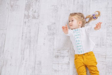 Neşeli bir kız yerde yatıyor. Çocuklar için moda.