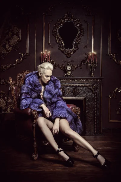 Portrait of a beautiful woman in luxurious fur coat posing in interior. Luxury, rich lifestyle. Fashion shot.